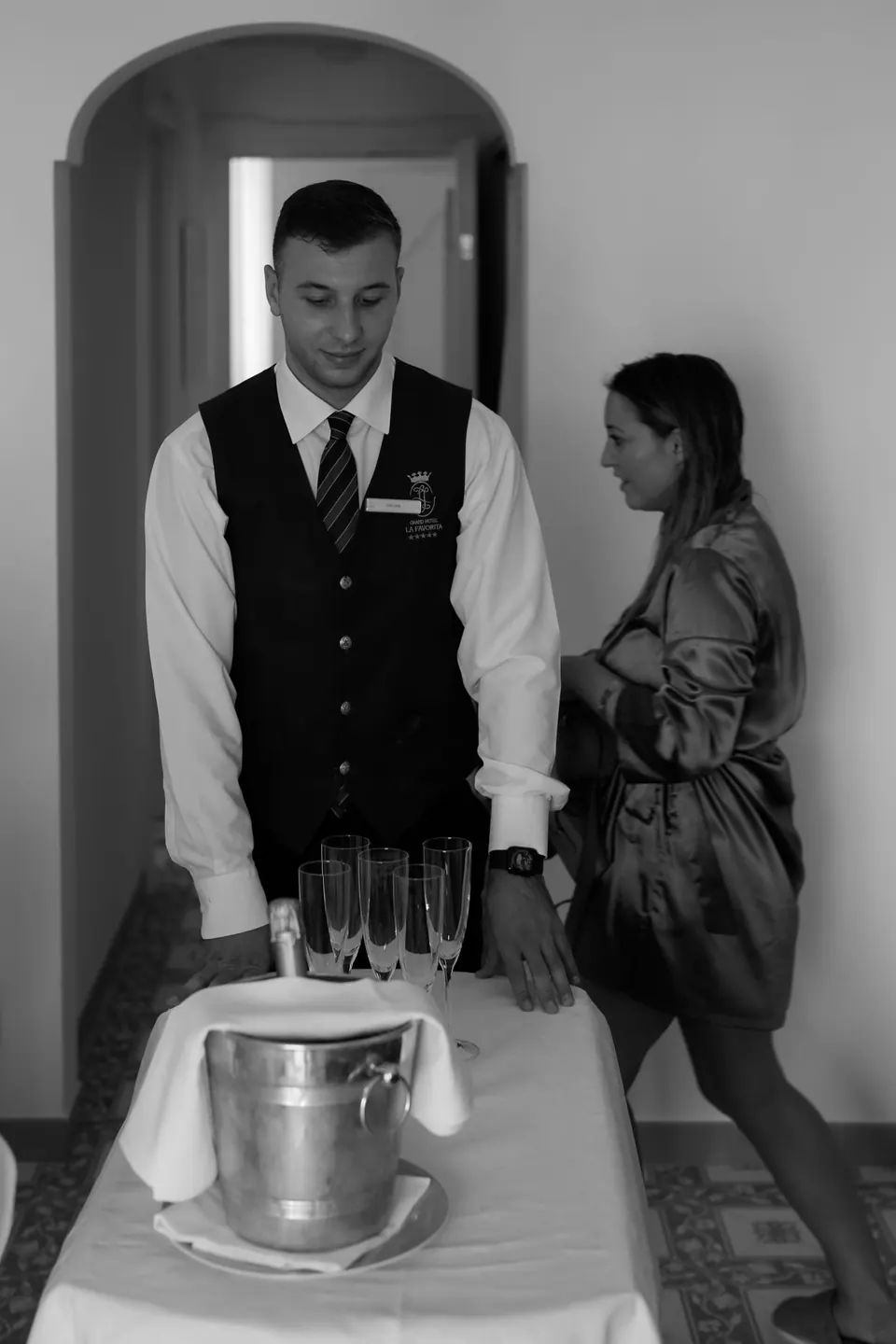 Black and white photo of a waiter preparing champagne in an ice bucket.
