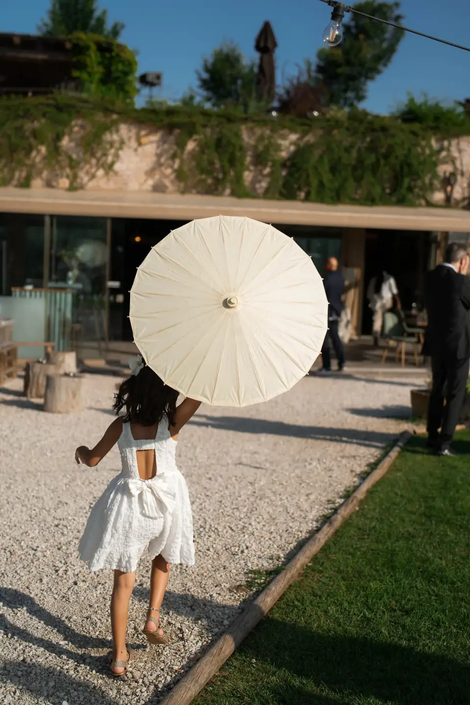 Guest with a white parasol walking along the gravel path at Borgo degli Antichi Orti.