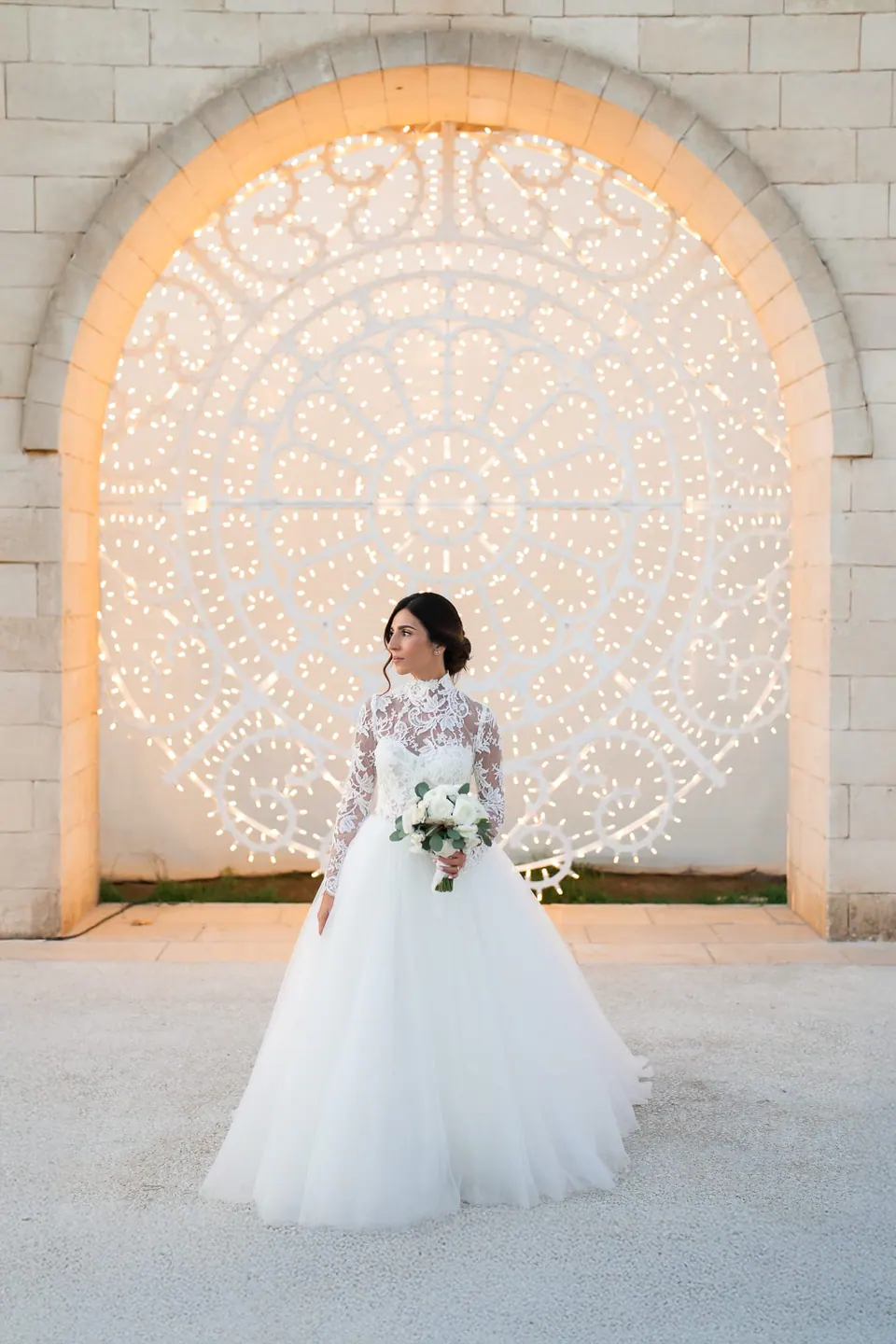 Bride in front of the illuminated carved stone arch of Tenuta San Domenico.