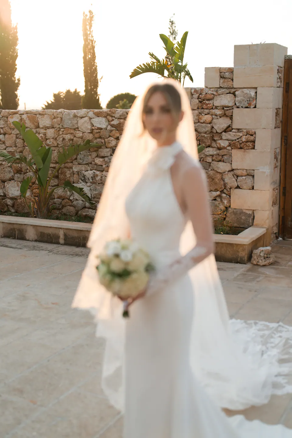 The bride holding her bouquet, the veil catching the warm evening light of Salento.