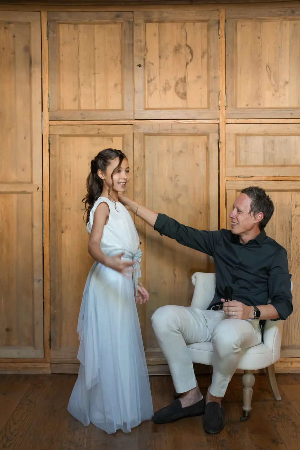 Bride standing by wooden panels beside a seated man