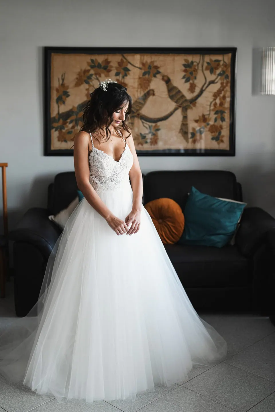 Bride in her gown standing by the window before the ceremony.