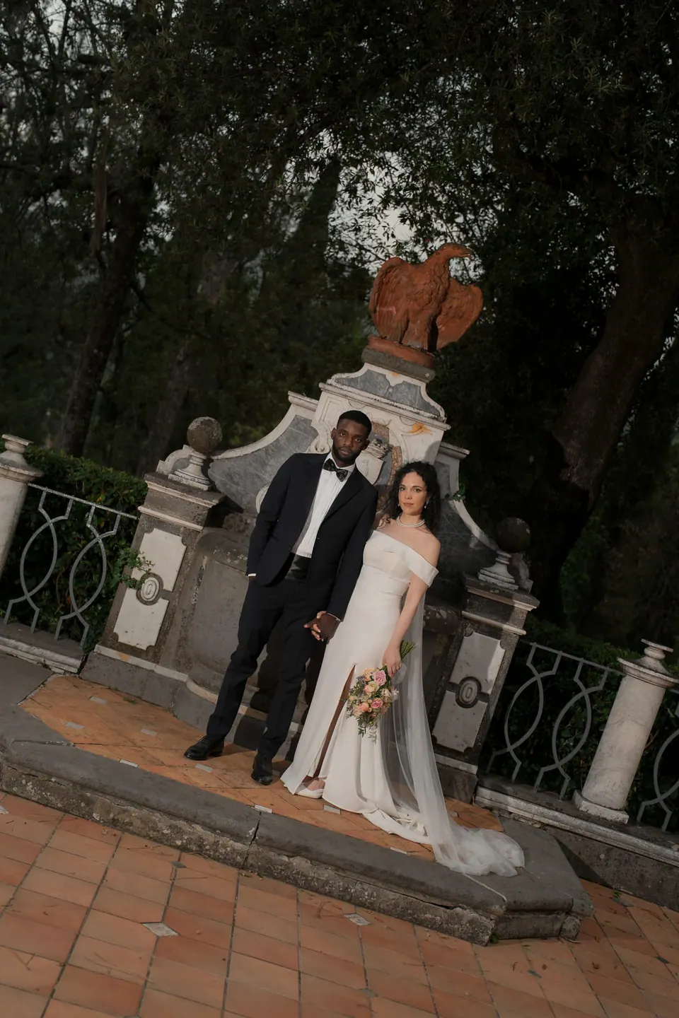 Bride and groom by the baroque stone fountain in the gardens of Villa Ortensia D'Avalos.